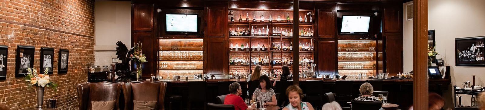A spacious restaurant interior with tables, booths, high ceilings, and a large bookshelf along one wall.- The Grand Hotel & Ballroom, McKinney