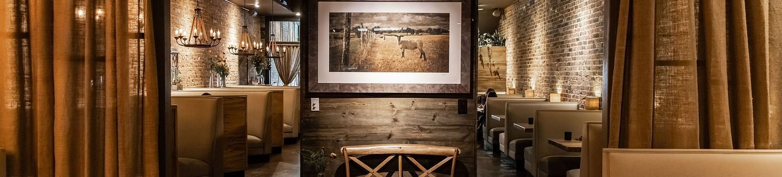 A dimly lit private dining space with booth seating, elegant drapes, and a framed artwork at the far end.- The Grand Hotel & Ballroom, McKinney