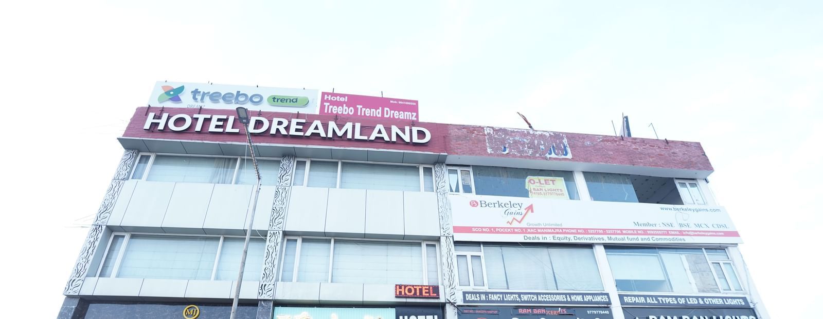 Facade image of Hotel Dreamland, Chandigarh with vehicles parked in the front.