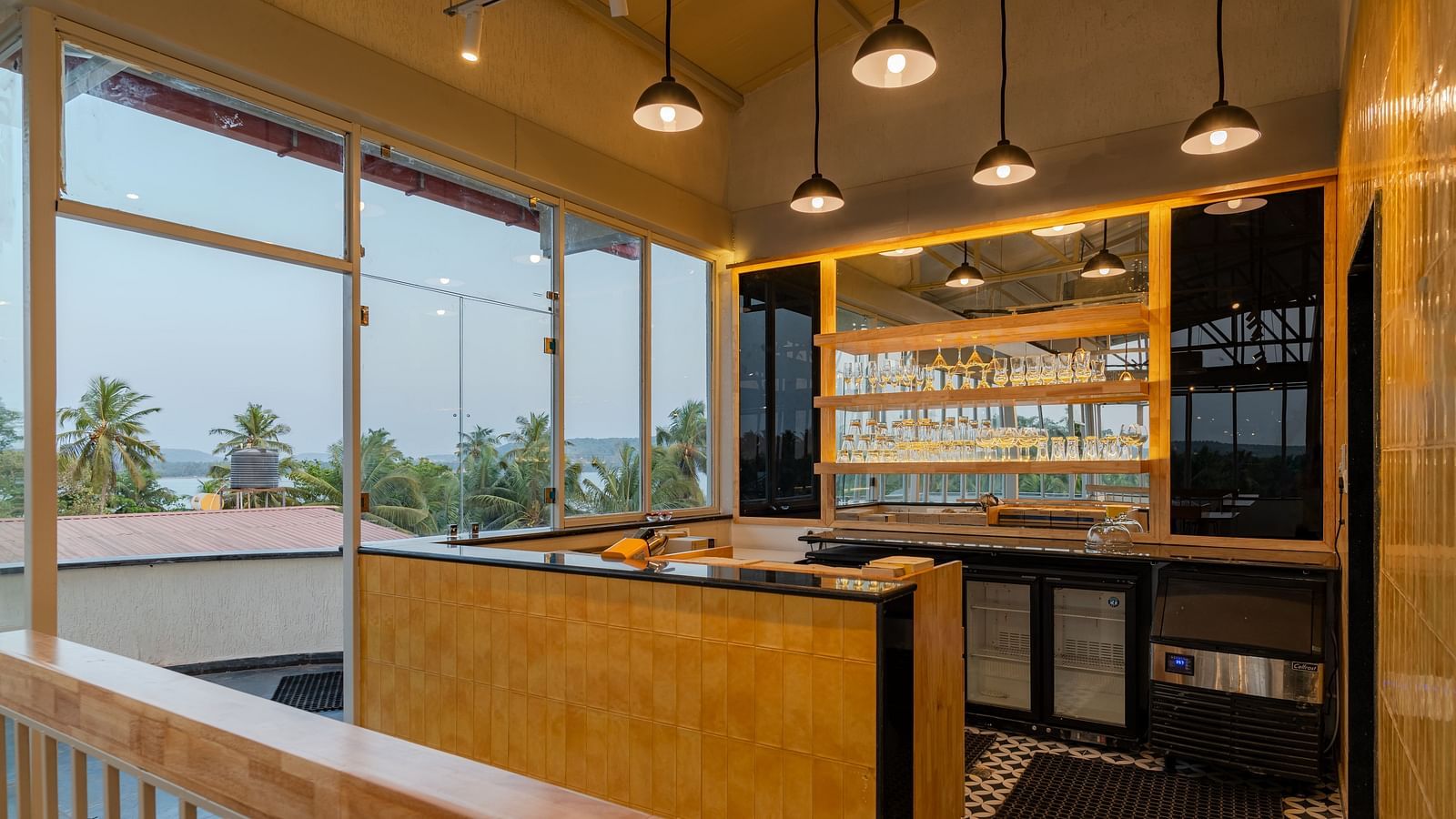 Interior of a contemporary cafe with bar stools and a window view. at Bedzzz Xclusiv Morjim, Goa