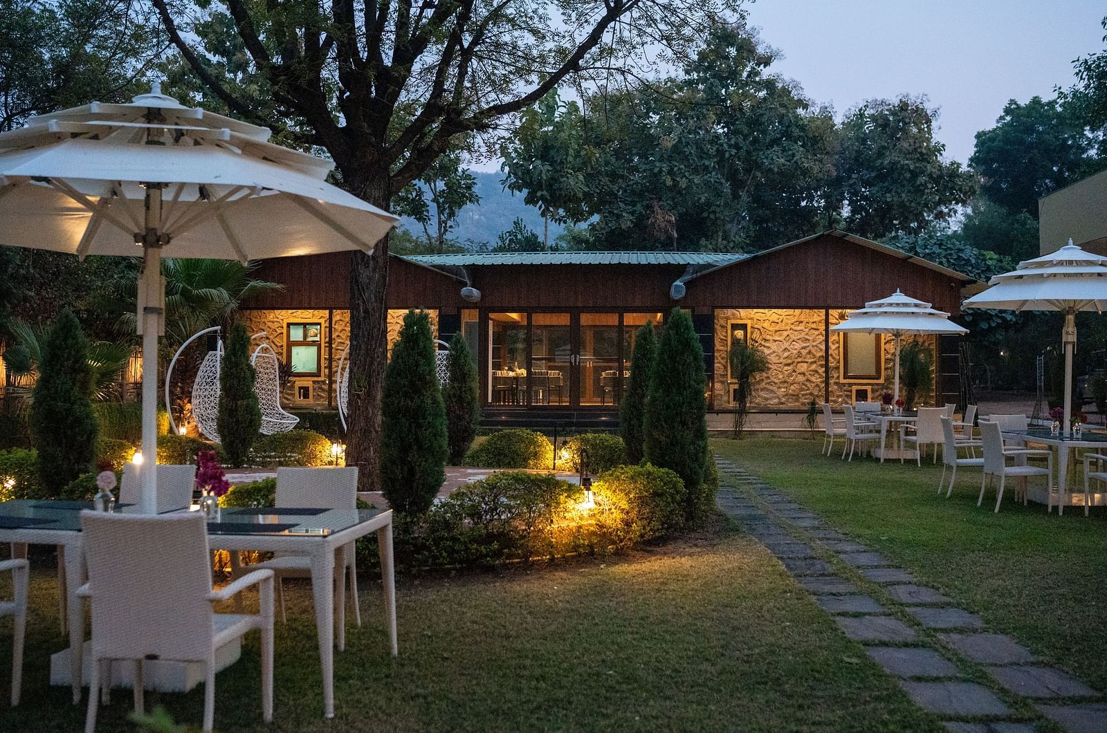 An evening view of the illuminated outdoor dining area at Aamaghati Jungle Retreat Ranthambore.
