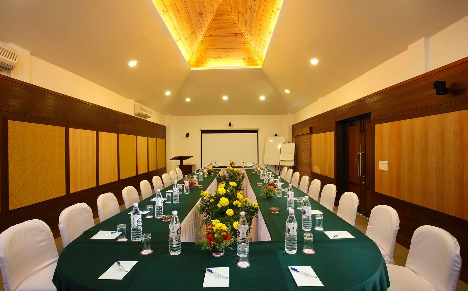Conference hall with arranged chairs and projector at baikunth Resort, Kasauli 