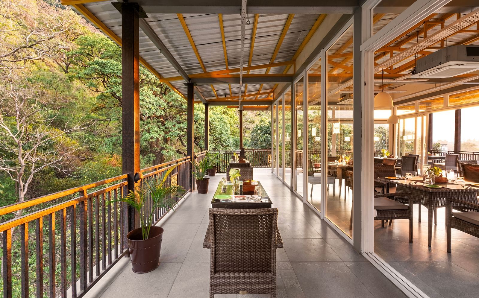 Balcony dining scene overlooking lush forest, with table set and chairs at Bedzzz, Rishikesh