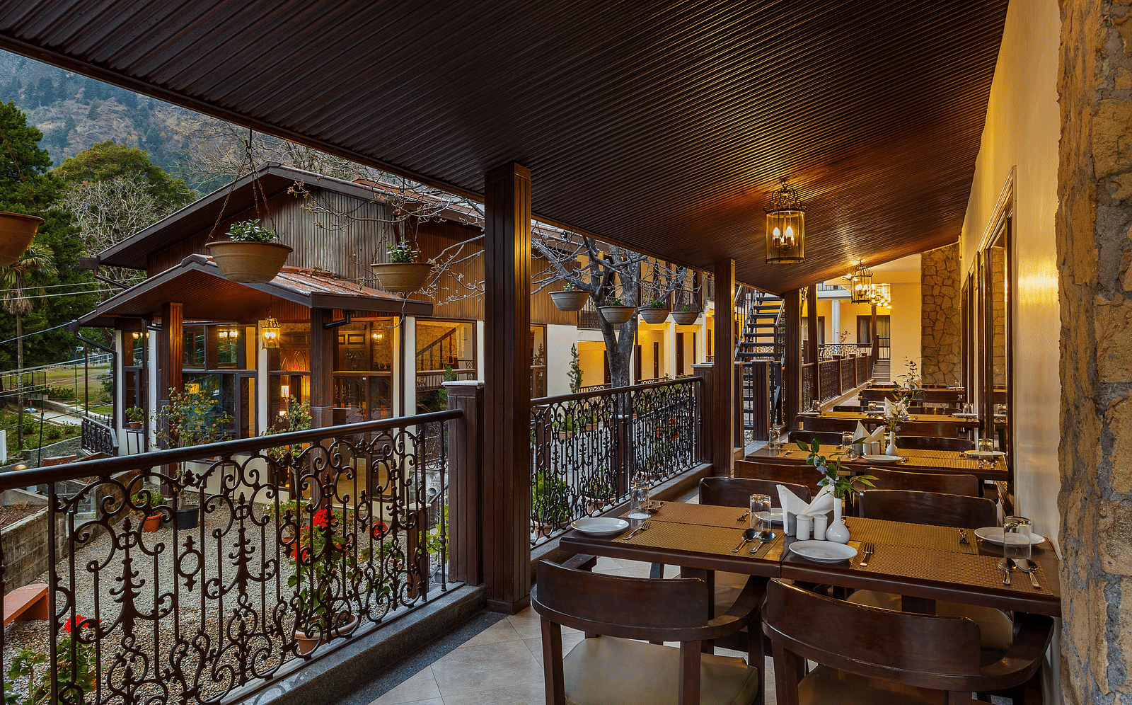 tables set up beside a wall on a balcony and flower pots hanging from the ceiling by the railing - The Earl's Court, Nainital