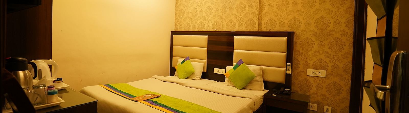 Standard Room featuring a double bed with green accents, a bedside table, and an air conditioning unit. - Hotel Dreamland, Chandigarh