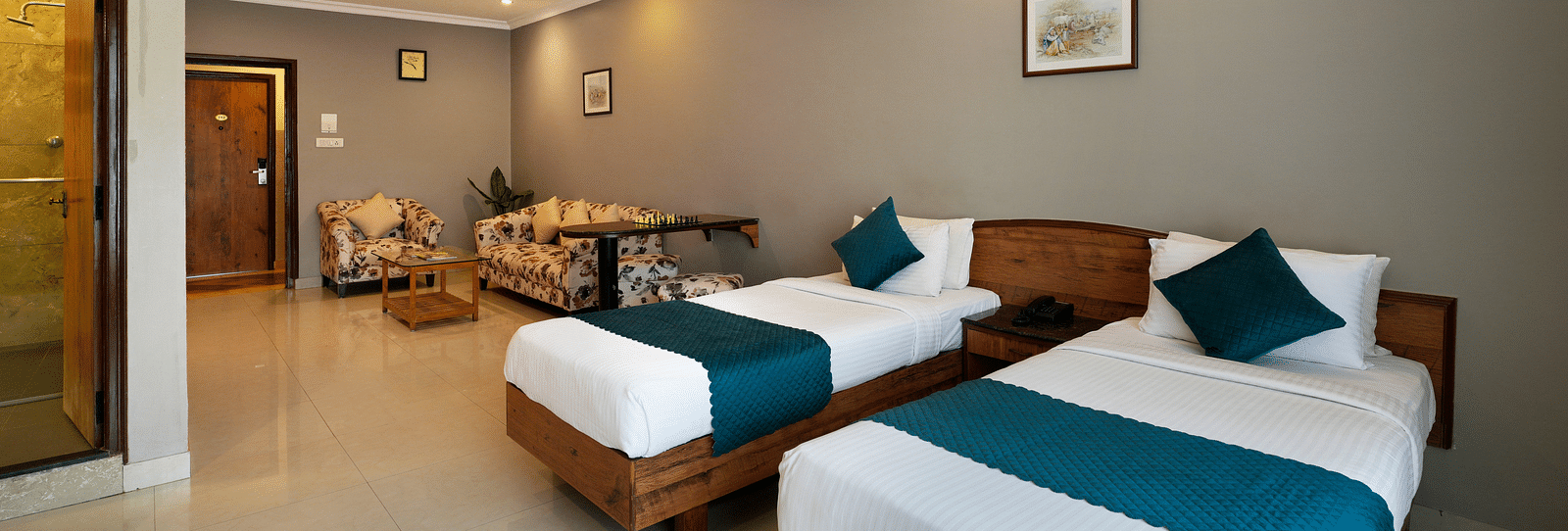 An image of an elegant Executive Room featuring twin beds and a seating area - Cross Roads Inn, Bengaluru