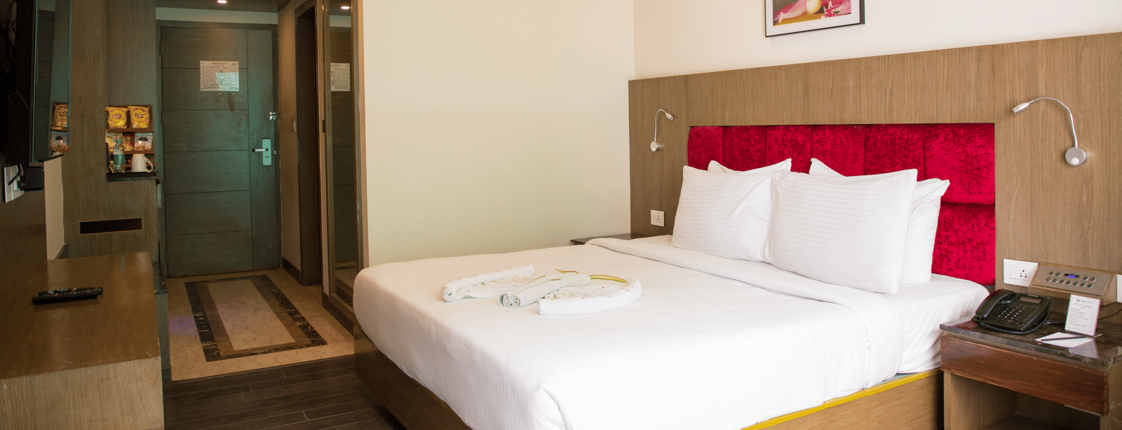 Side view of the Deluxe Room with ample of natural light coming inside featuring a double bed along with the entrance to the room at the Benzz Park, Vellore.