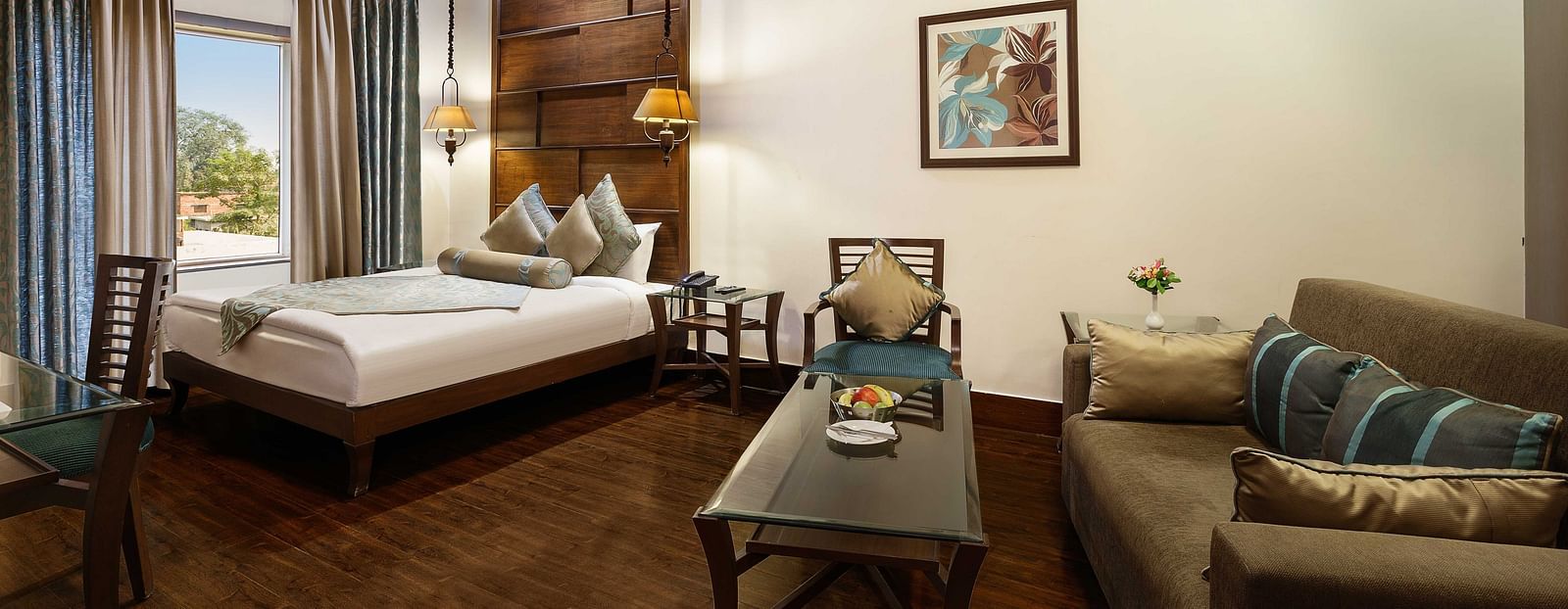 a view of a bedroom with a large bed in the corner and a sofa with a table - The Manor, Kashipur