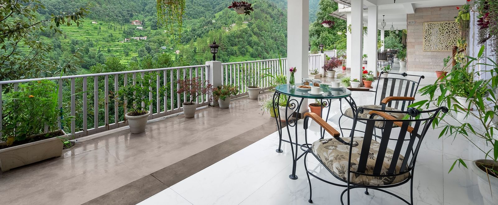 Open-air veranda with seating and potted plants overlooking forested hills, at BluSalzz Collection - Suvaasa Resort, Ramgarh.