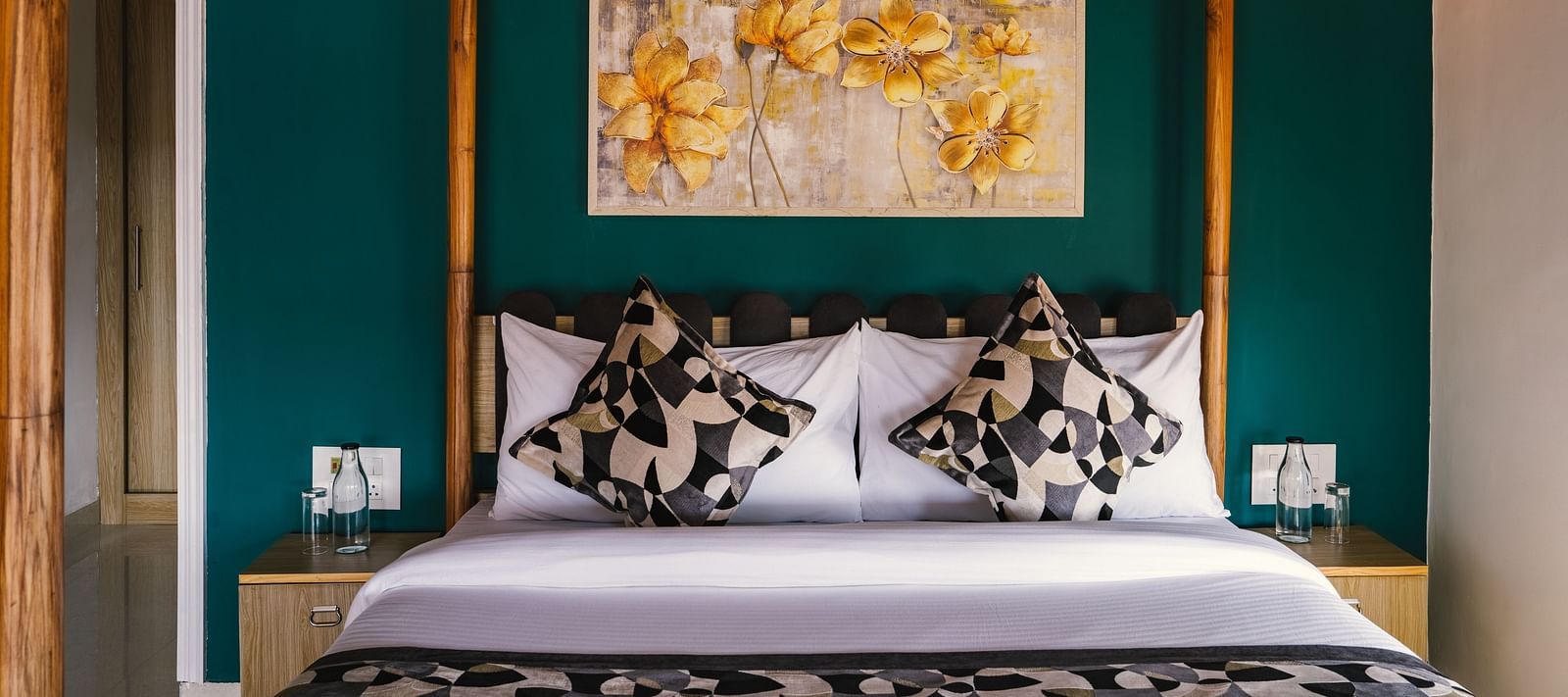 A neatly made bed with a photo frame above the headboard, a bedside table on each side, and a wooden frame at BluSalzz Villas - The Green Roof, Bhimtal.