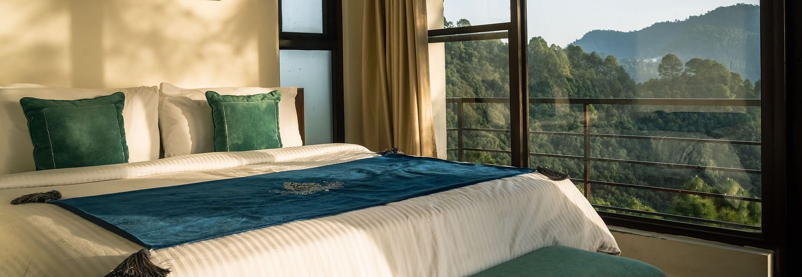 A bedroom with a balcony offering a mountain view and sunlight streaming in at BluSalzz Escapade Resort, Lansdowne
