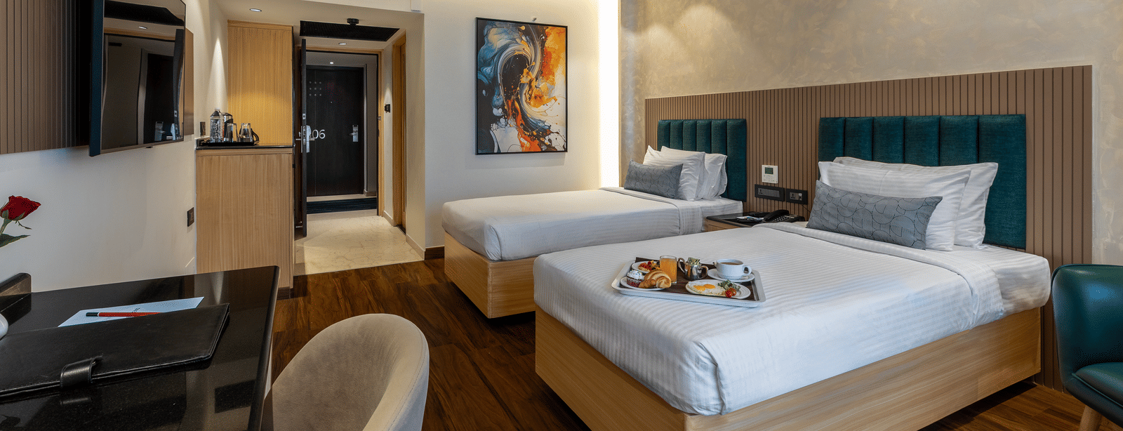 A well-lit hotel room at the Citrine Hotel with twin beds, a TV, and a mirror.