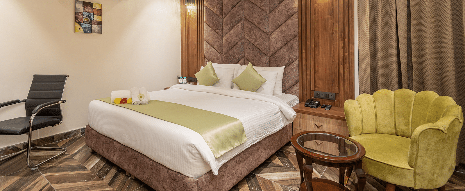 Image of Deluxe Room at DLS Grand Luxotica, Dehradun featuring a plush bed with a sitting space next to it by the window 