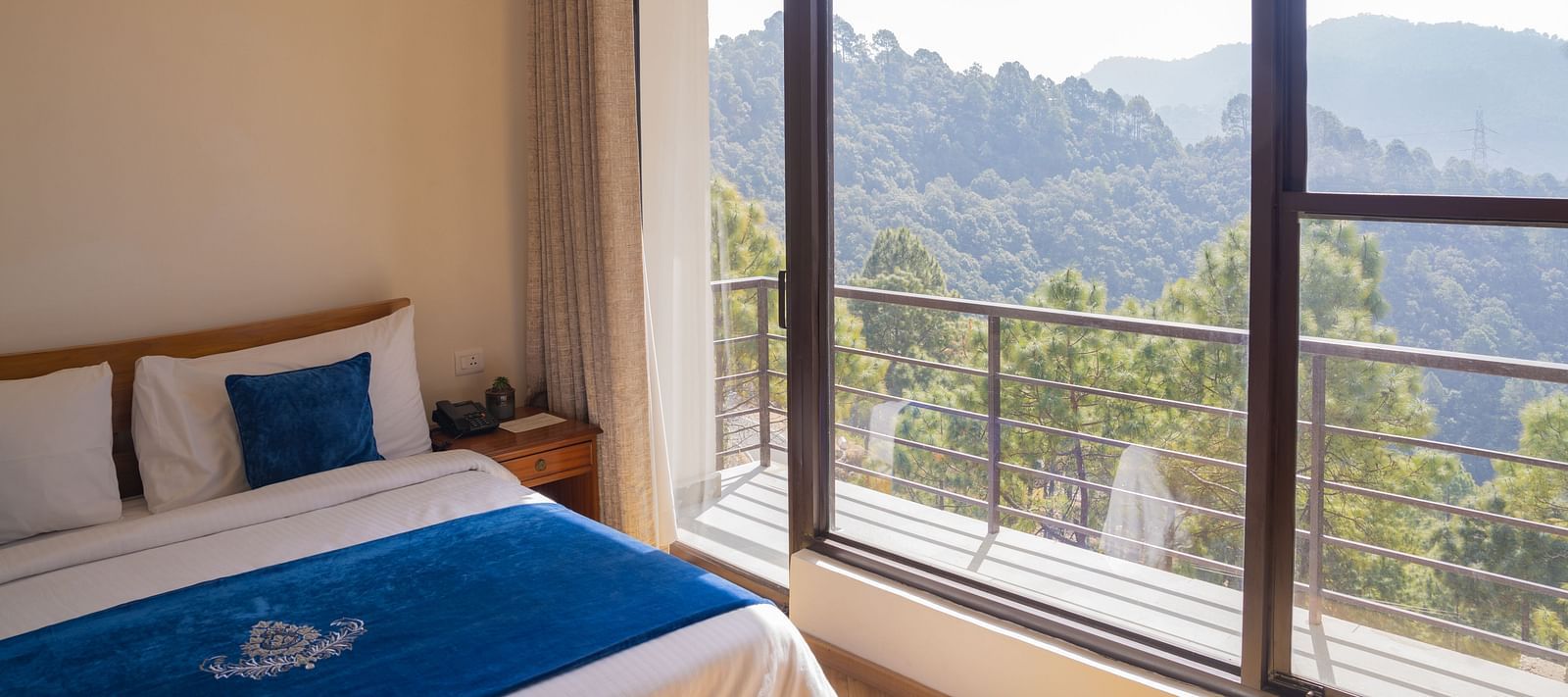 A bedroom with a balcony offering mountain views at BluSalzz Escapade Resort, Lansdowne.
