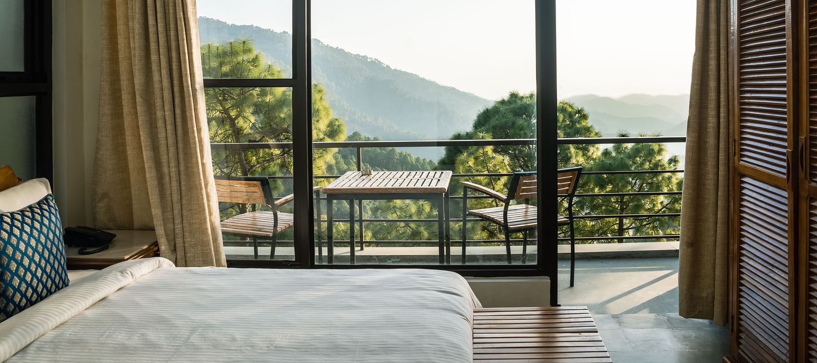 A bedroom with a balcony offering natural light and scenic views at BluSalzz Escapade Resort, Lansdowne