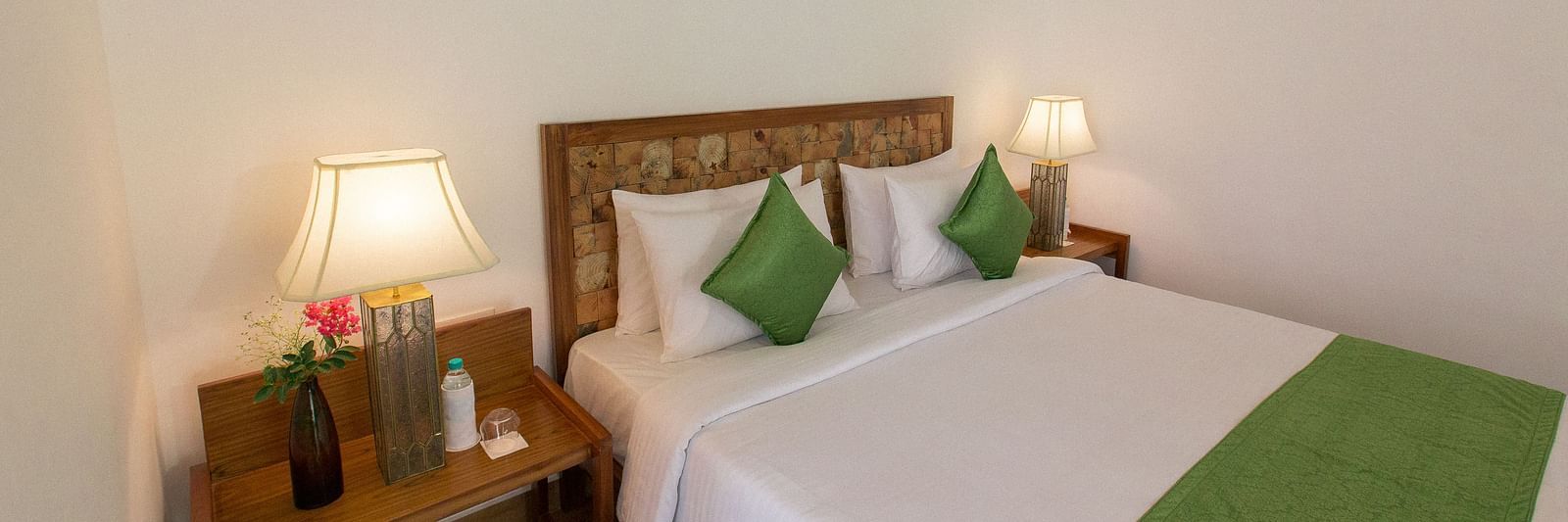 A room at Saraca Resort & Spa Corbett with a double bed and side tables with bed lamps placed on top of them