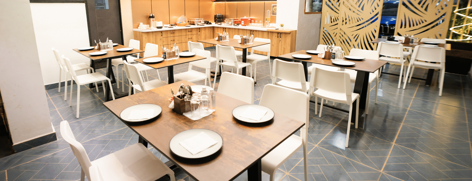 Restaurant seating area with tables and chairs set for dining at Sunrise Business Hotel, Hyderabad.