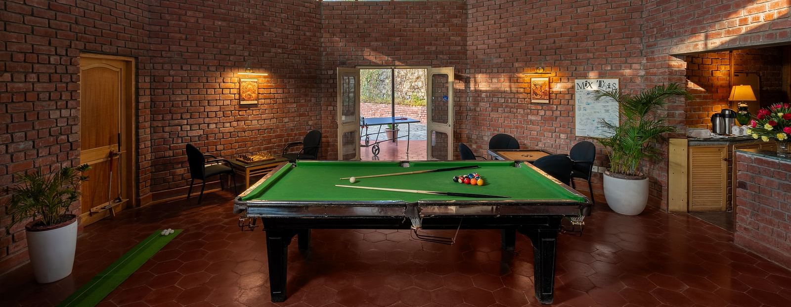 A pool area with a glass roof, indoor plants and room is illuminated by lights -  Baikunth resort, kasauli 