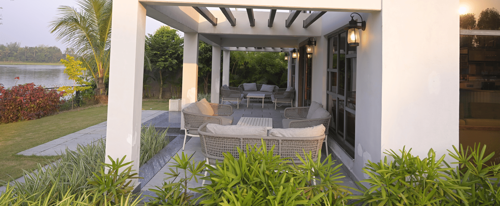 A shaded patio lounge set amid lush garden landscaping, offering a peaceful open-air setting at Hotel Sonar Bangla Mayapur.