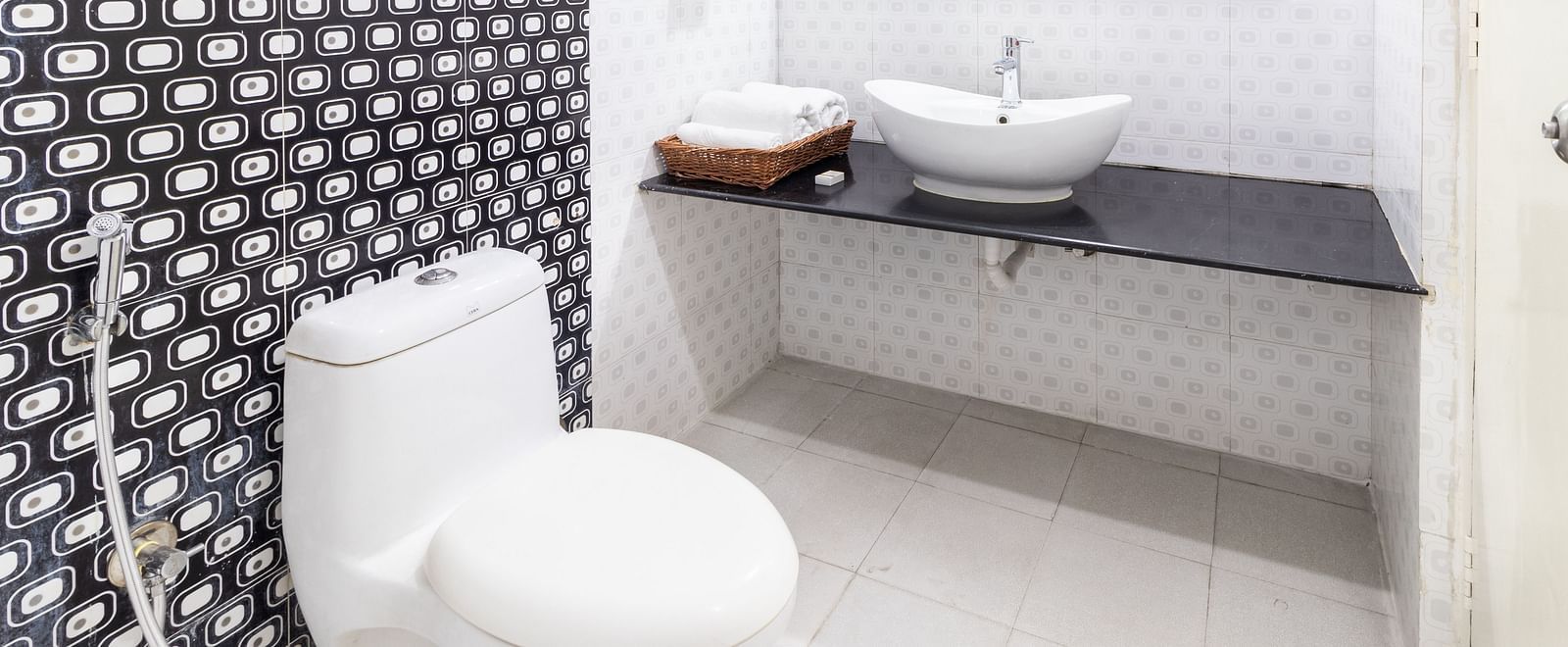 A bathroom featuring a toilet, a sink, and toiletries placed on the counter-top at Sanctum Suites Domlur, Bangalore.