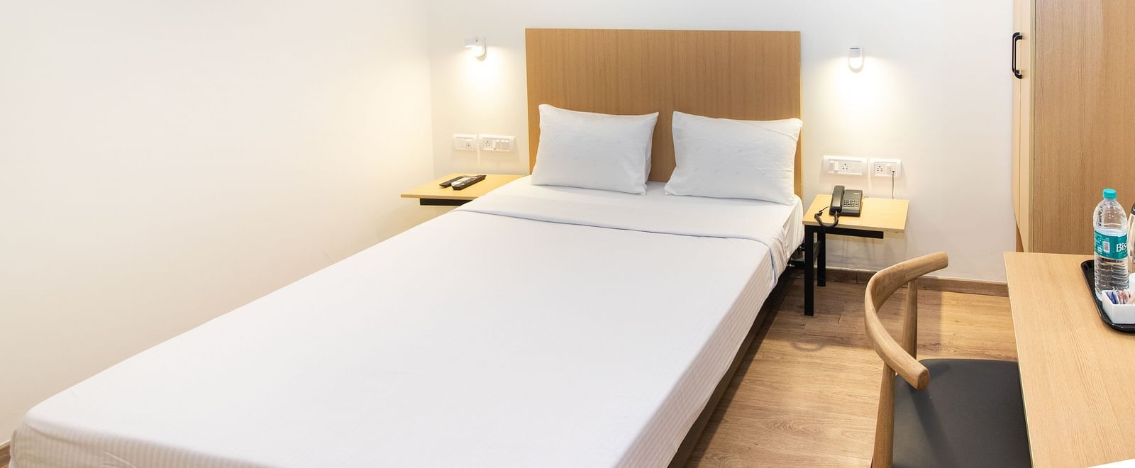 Bedroom with a single bed, white covers, a bedside table, and a work desk and chair - Sanctum Suites Richmond Road, Bangalore