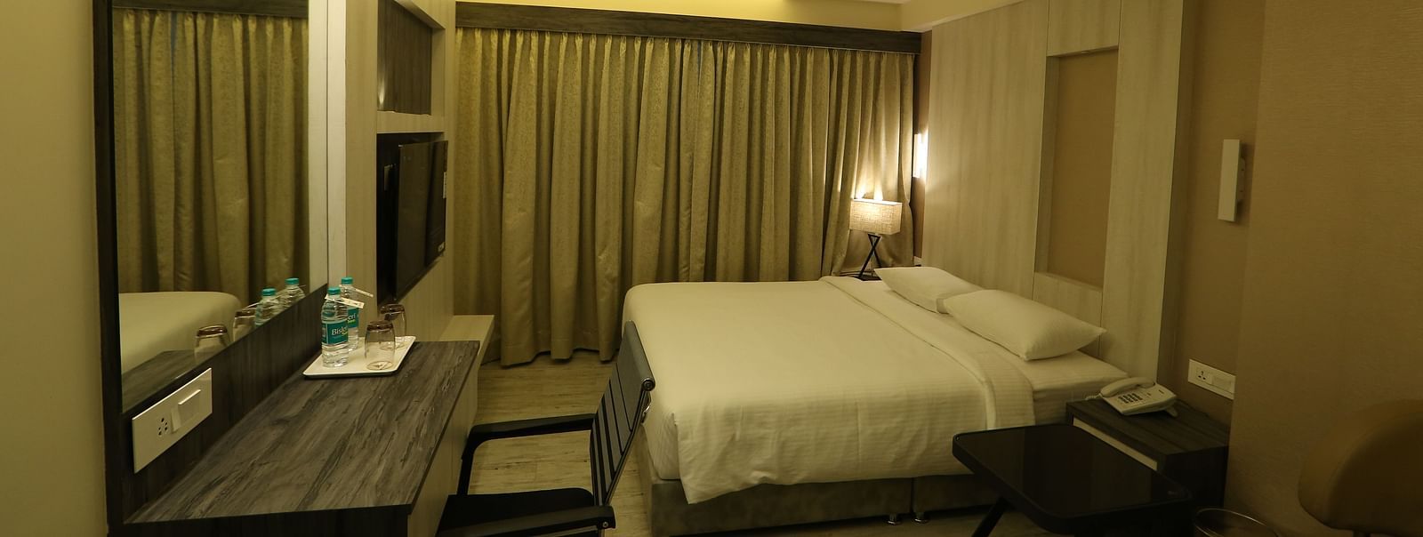 Premium Room featuring a king size bed, desk with a mirror, chair, and ambient lighting, showcasing the room's layout and decor - TGI SPS Grand, Coimbatore