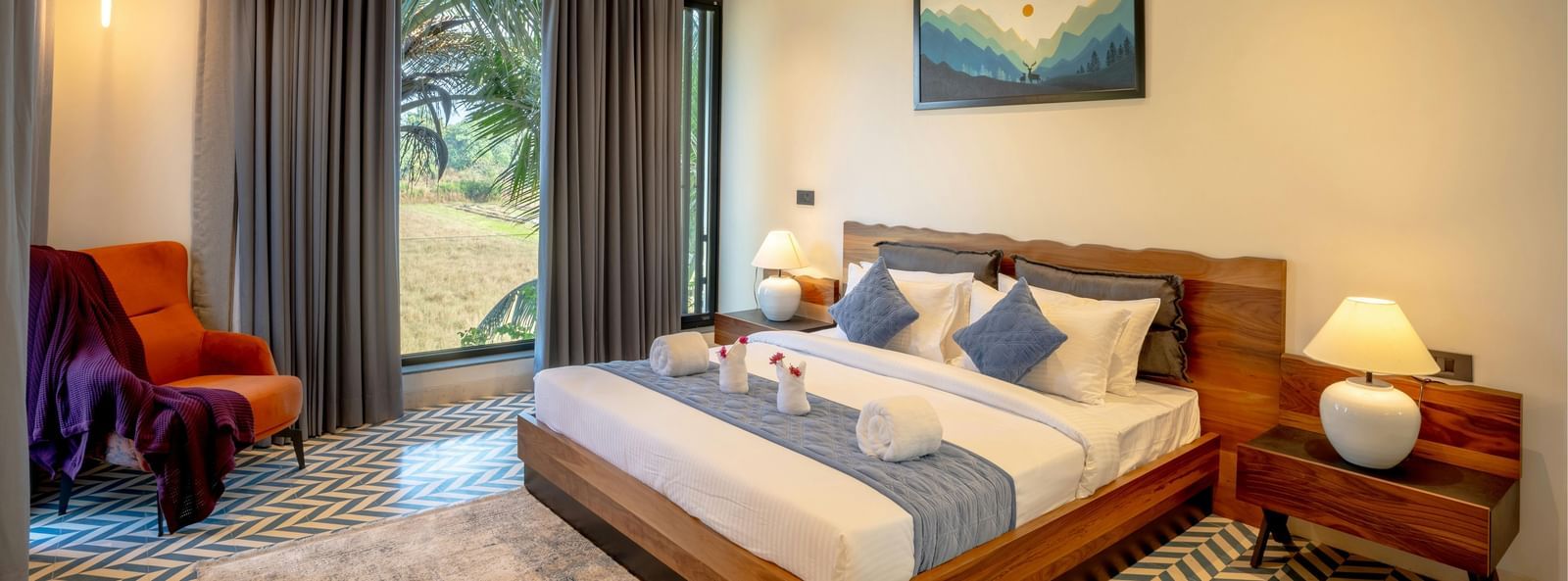 A cosy room featuring a neatly made bed, matching side tables, a large window that fills the space with natural light, and contemporary furnishings