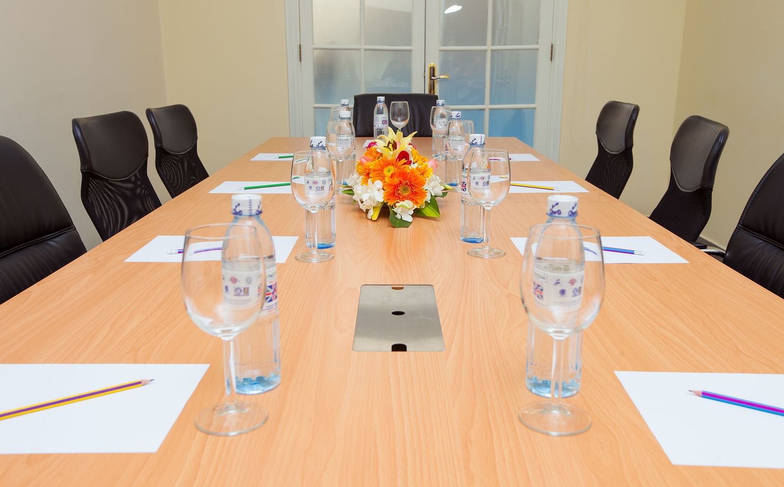 A meeting room with a long table, chairs, and glasses | Conference Hall | Central Mansions, Phnom Penh