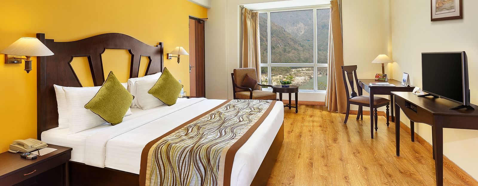 An image of the room features a king-size bed with a plush headboard and colorful bedding. A comfortable armchair sits by the window, offering a view of the outdoors. 