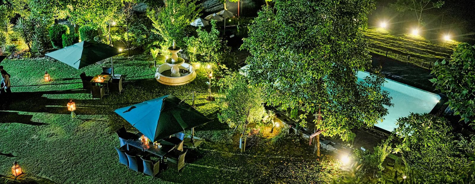 An image of campsite with tents lit up at night, surrounded by trees, capturing an arial view 