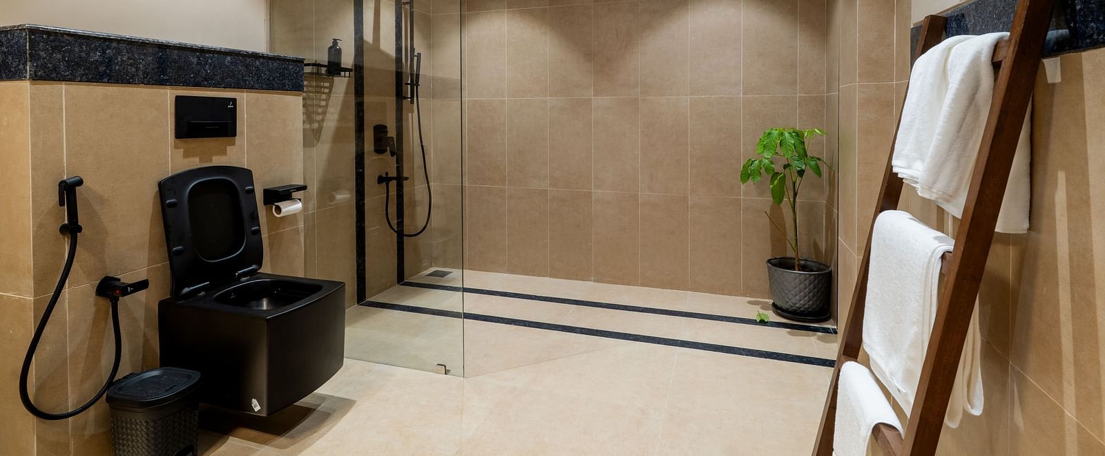 Modern bathroom with walk-in shower, black fittings, and towel racks at Kssemya.