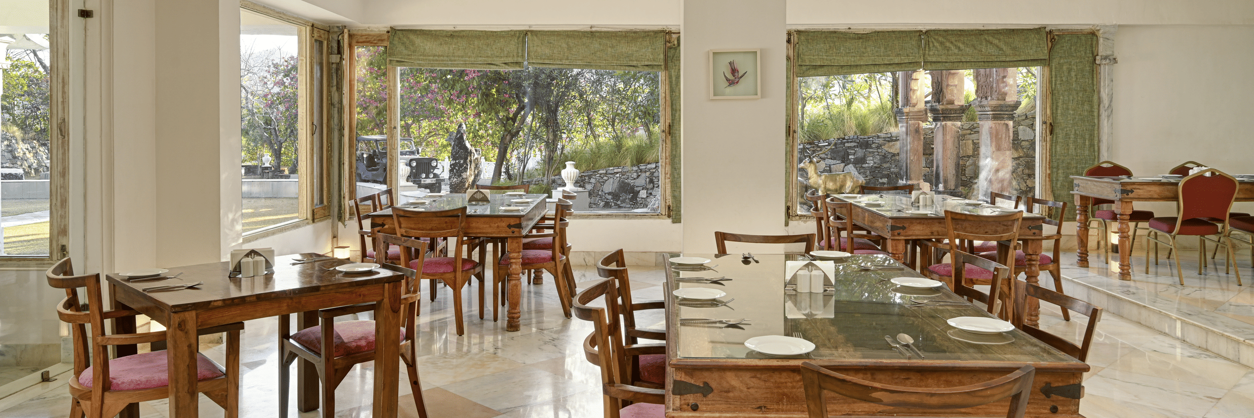 Lobby restaurant at Fateh Safari Resort, Kumbhalgarh featuring sets of tables and chairs and a view of outdoor.