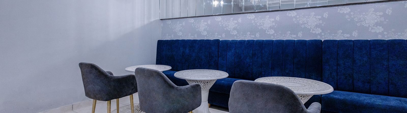 corner view shot of the restaurant with three round tables with a huge blue couch in front of it - Hotel Downtown17, Chandigarh