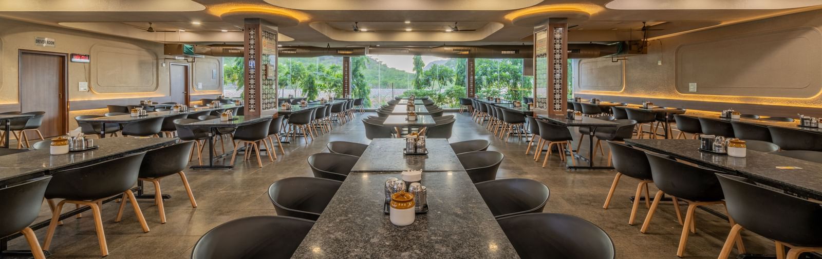 A spacious interior dining hall with modern table and chair settings at Hotel Highway King, Neelka.