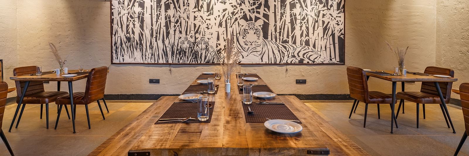 A dining area with wooden benches and tables and chair for seating at Trees N Tigers, Tadoba.