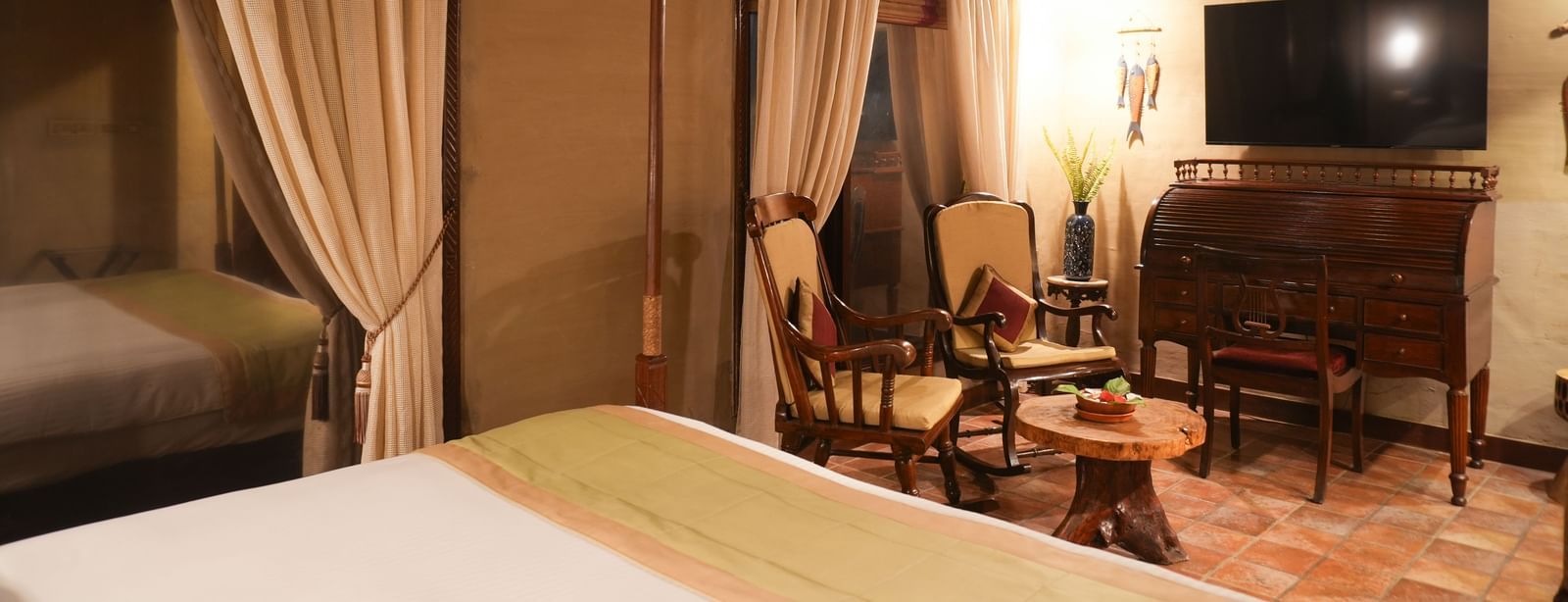 A corner of the Zamindar Suite at Vedic Village Spa Resort with two lounge chairs, a TV, and terracotta accent tiles.