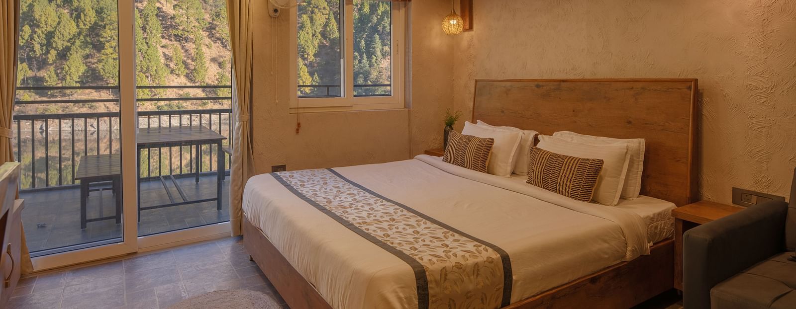 Room with double bed, balcony doors, wooden beams on the ceiling, and soft lighting.