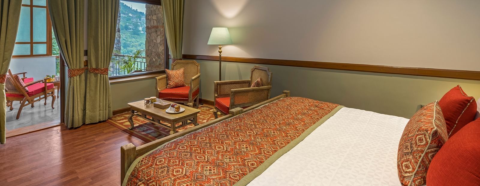 Top head view of Superior Rooms showcasing a cosy, royal interior with a comfortable bed, chair, and table, complemented by a beautiful hill view.