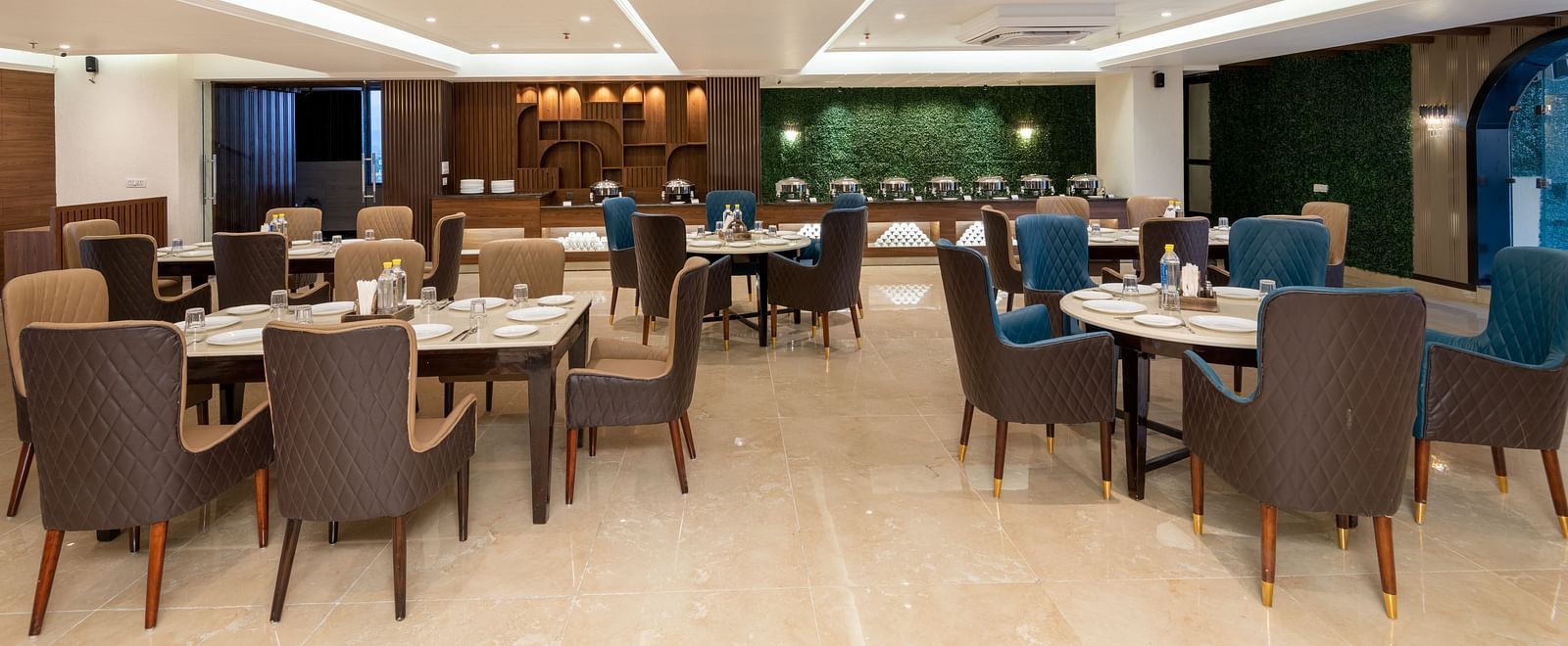 The restaurant at DLS Grand Luxotica, Dehradun with chairs and tables with warm lighting