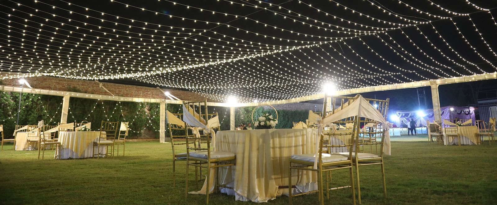 Outdoor lawn setup with fairy lights and banquet seating for events at Tisya Farms, Gurgaon.