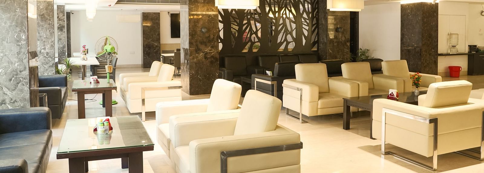 An elegant lounge or common area at BNGV Grandeur Hotel and Banquets, with light-colored furniture and unique ceiling light fixtures.