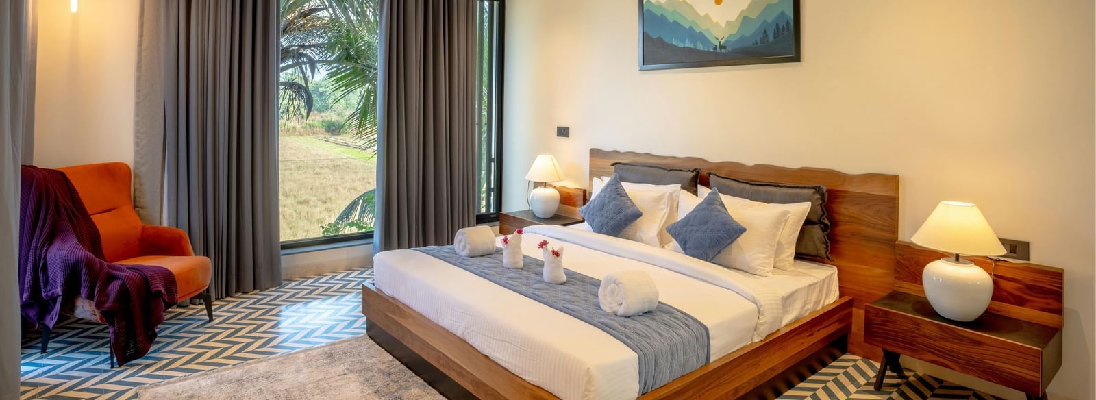 A cosy room featuring a neatly made bed, matching side tables, a large window that fills the space with natural light, and contemporary furnishings
