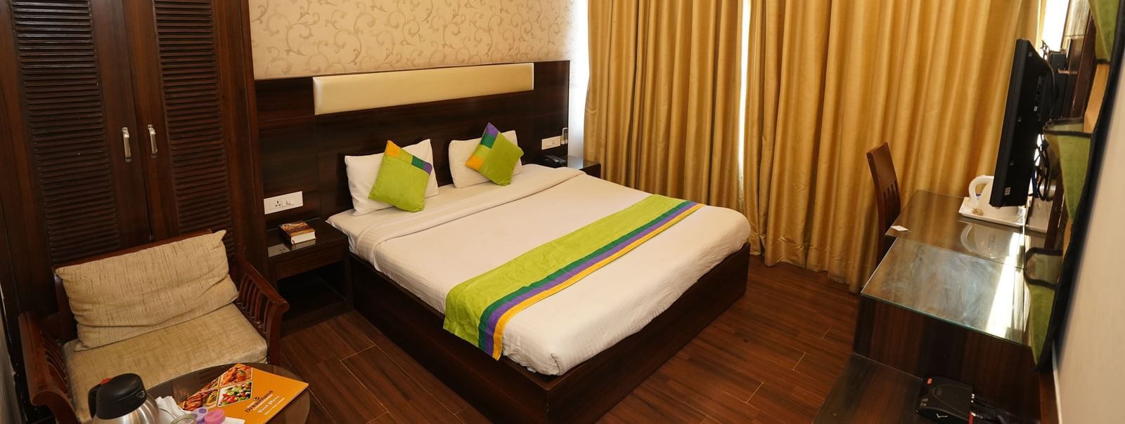 Deluxe room at Hotel Dreamland, Chandigarh features a king-size bed, work table and a wooden wardrobe. 