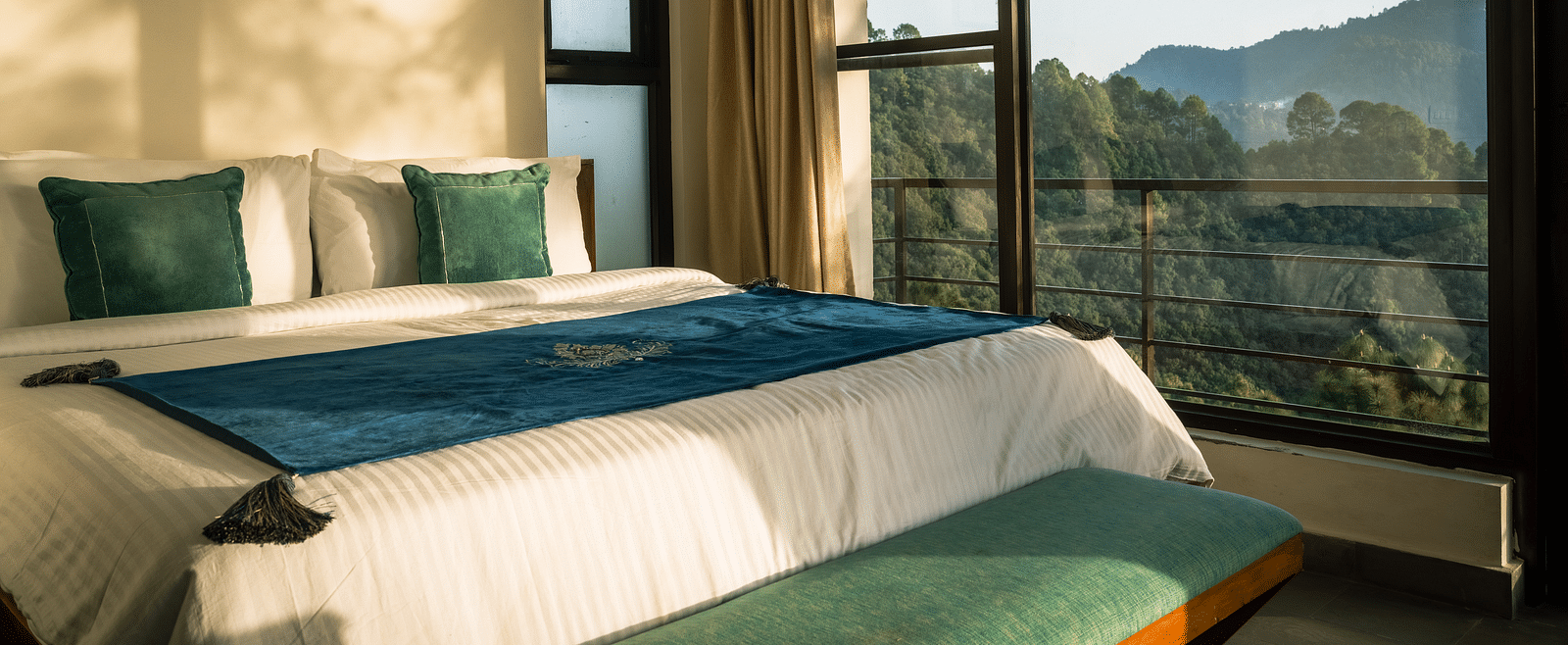A bedroom with a balcony offering a mountain view and sunlight streaming in at BluSalzz Escapade Resort, Lansdowne