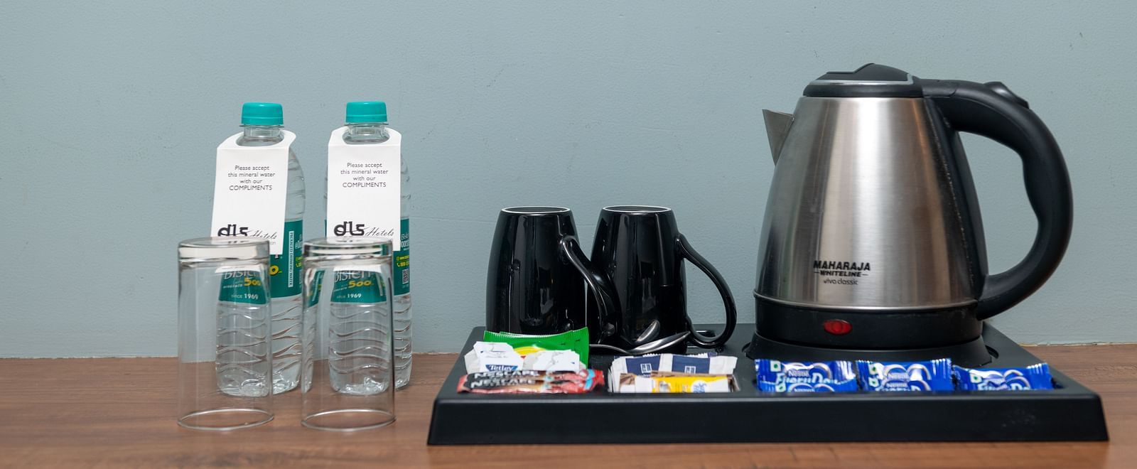 A close up shot of an electric kettle, two coffee mugs, and two bottled water - DLS Ganga Bliss, Haridwar