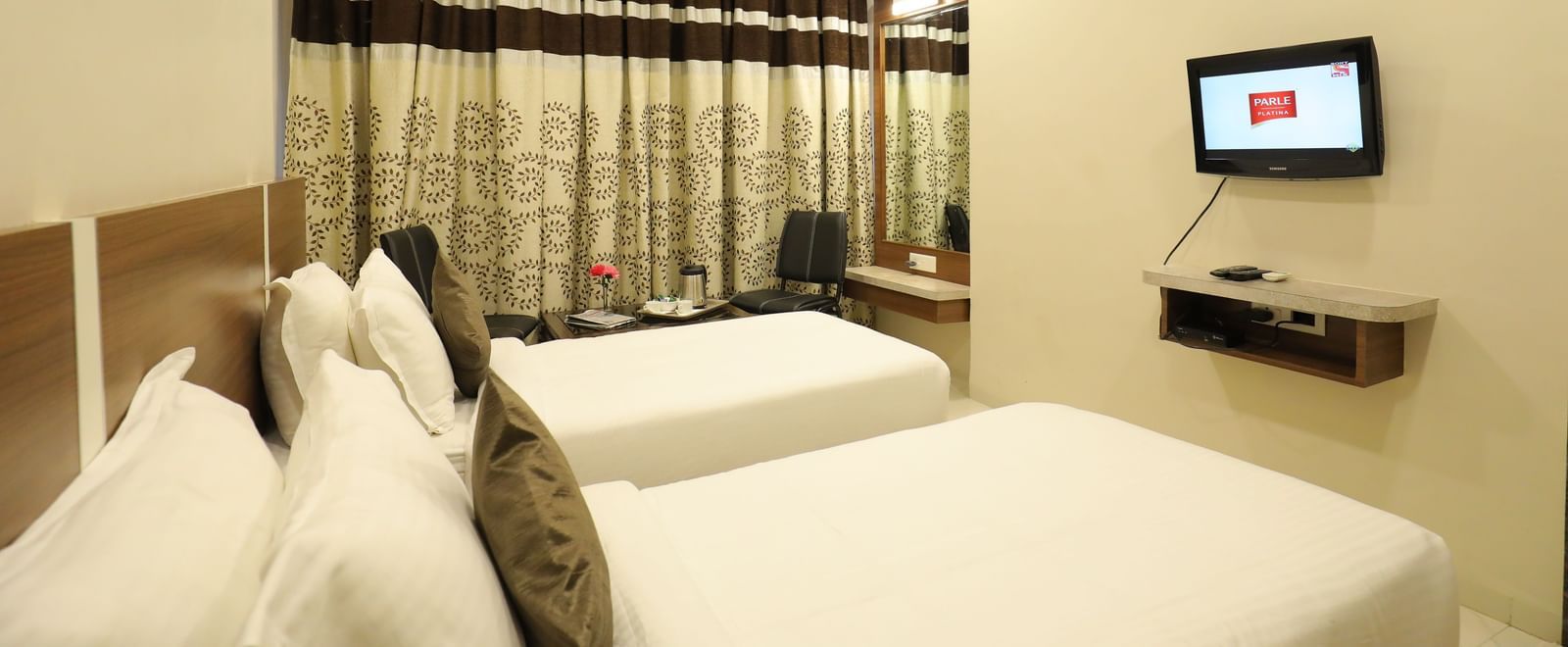 Corner view of twin beds in the Super Deluxe Rooms of Highland Resort, facing a wall-mounted TV.