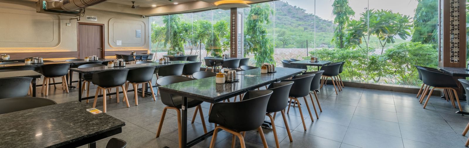 Restaurant interior showing a dining space and panoramic window view of the surrounding hills at Hotel Highway King, Neelka.