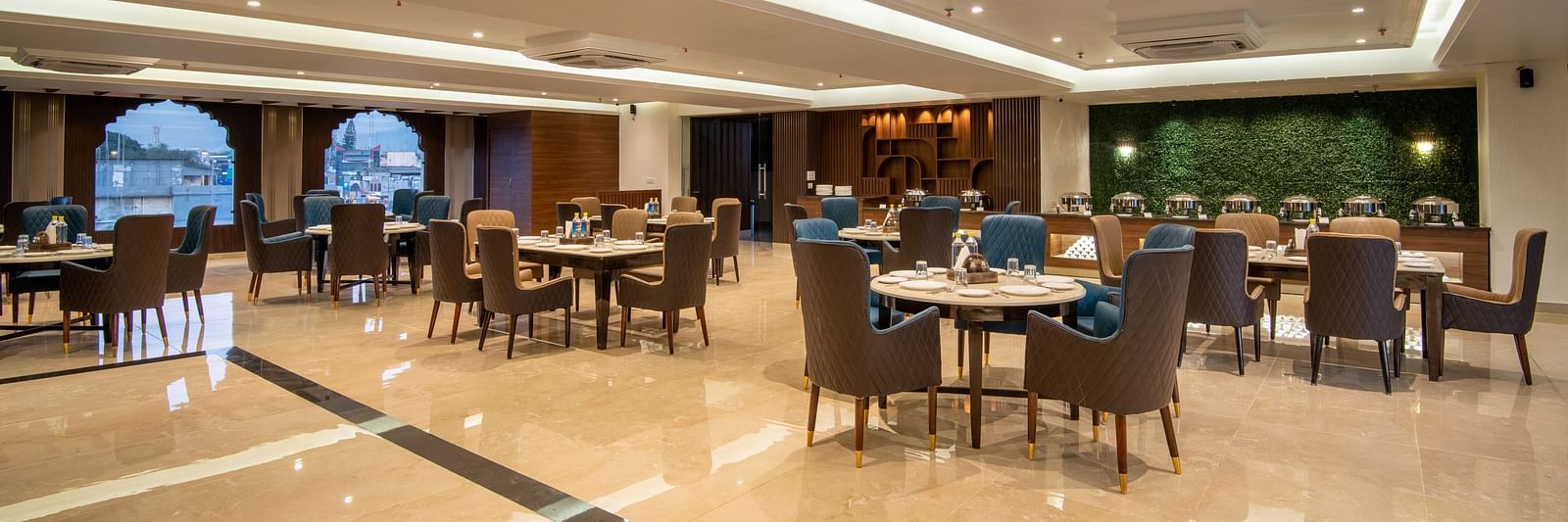 A shot of Ruttba, one of the best restaurants in Dehradun featuring chairs and tables with warm interior lighting - DLS Grand Luxotica