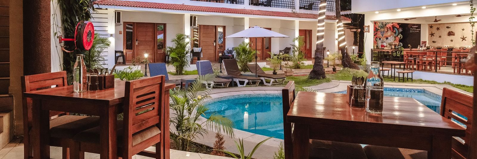An inviting poolside dining area with wooden tables – The Verda de Miranda Resort.