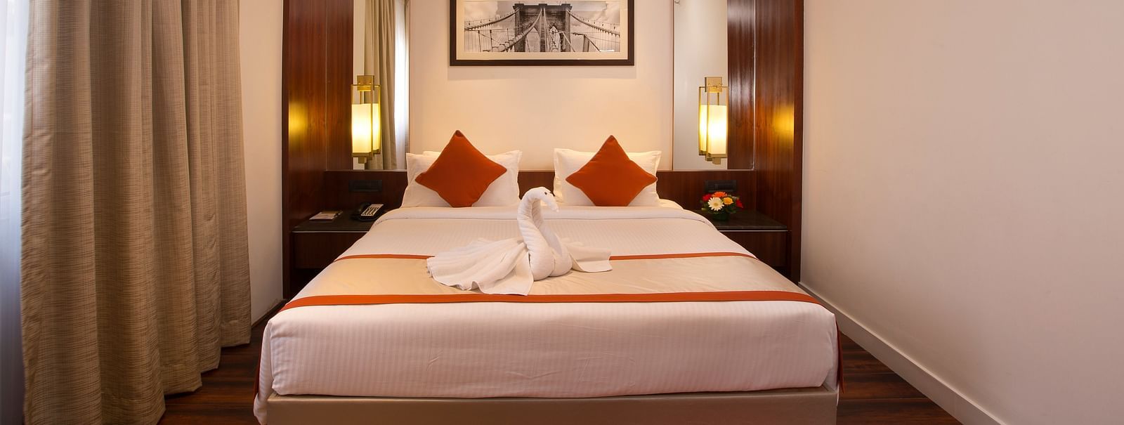 A hotel room featuring a large bed with white linens and red accents, a desk and a wall-mounted TV - Hotel Southend by TGI - Bommasandra, Bangalore